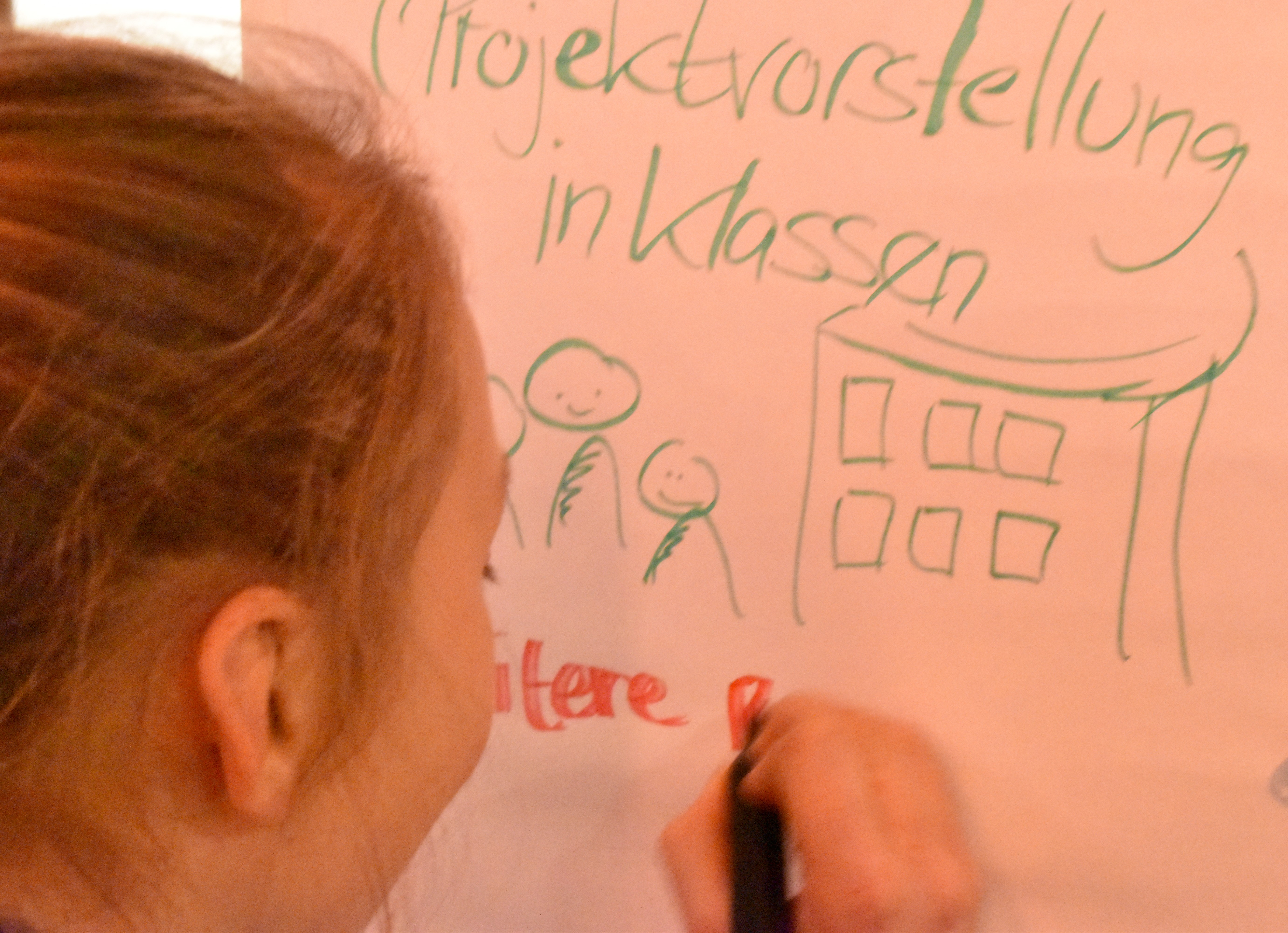 Kind schreibt eine Idee auf ein Plakat